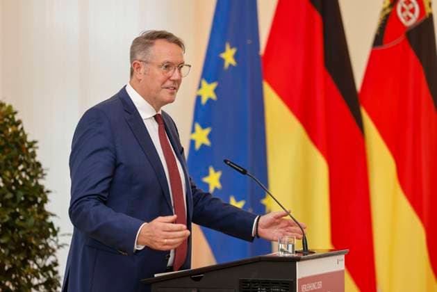 Rhineland-Palatinate Minister President Alexander Schweitzer at the lectern in front of flags in the State Chancellery of Rhineland-Palatinate Speech on the occasion of the awarding of professional titles of the state 03 09 24