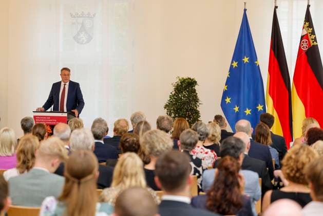 Rhineland-Palatinate Minister President Alexander Schweitzer at the lectern in front of flags in the State Chancellery of Rhineland-Palatinate Speech on the occasion of the awarding of professional titles of the state 03 09 24