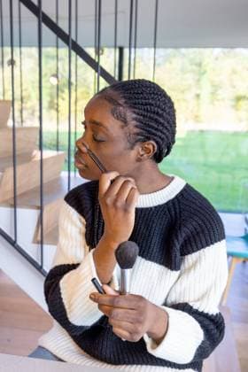 IMAGO Creative, Naturkosmetik Focused Woman Applying Makeup with Brushes at Home In a setting filled with natural light, a woman with intricately braided hair applies makeup with precision, using a variety of brushes. The scene is casual yet intimate, highlighting a moment of self-care and beauty routine in her home environment. Focused Woman Applying Makeup with Brushes at Home. High quality photo ,model released, Symbolfoto Copyright: xZoonar.com BjornxBeheydtx 21487567 ,model released, Symbolfoto ,property released