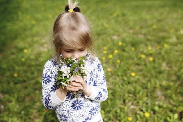 Creative Highlights Symbolfotos Kleines Mädchen schnuppert an Frühlingsblumen auf grünem Rasen im Garten Little girl sniffing spring flowers on green lawn in the garden. Copyright: imageBROKER LenaxIvanova ibxiqx11147385.jpg ,model released, Symbolfoto ,property released