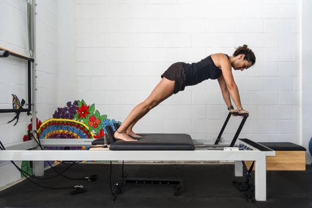 Eine Frau in der Plank Position auf einem Pilates Reformer in einem Fitnessstudio A woman doing a plank position on a Pilates reformer in a gym setting Copyright: imageBROKER JuanmaxCuevas ibxjcu10756142.jpg ,model released, Symbolfoto ,property released