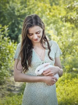 Creative Highlights Symbolfotos Niedliches Porträt einer jungen Frau, die ein weißes Kaninchen in ihren Armen hält, vor einem grünen Gartenhintergrund. Mädchen streichelt ein entzückendes Kaninchen Cute portrait of a young woman holding a white bunny in her arms over a green garden background. Girl petting an adorable rabbit Copyright: imageBROKER VeaceslavxBordeianu ibxveb11066976.jpg ,model released, Symbolfoto ,property released
