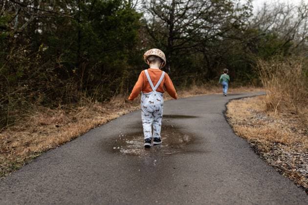 Creative Highlights Symbolfotos young boy in suspenders jumping in puddle on paved rural path Norman, Oklahoma, United States CR_AOVS240918B-1532623-01 ,model released, Symbolfoto