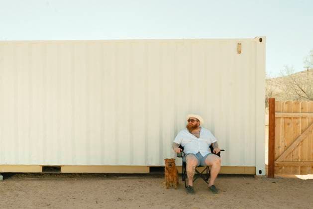 Creative Highlights Symbolfotos Man in a chair with a small dog beside a white container in the deser Joshua Tree, California, United States CR_QCYJ240904-1531025-01 ,model released, Symbolfoto