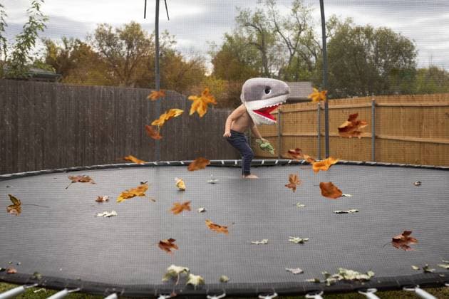 Creative Highlights Symbolfotos boy in shark costume on trampoline with fall leaves on cloudy day Norman, Oklahoma, United States R_AOVS240905A-1532713-01 ,model released, Symbolfoto