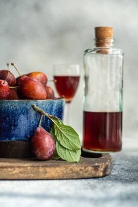 IMAGO Creative, Jahreszeit Sommer, Food, Pflaume A bowl of fresh, organic plums alongside a bottle of homemade plum liqueur, captured from the side. The image highlights ripe plums with vibrant colors and a glass of plum liqueur, suggesting a cozy, autumnal setting. Model Released AnnaBogush_ID23878_692882_013 Copyright: xAnnaxBogushx