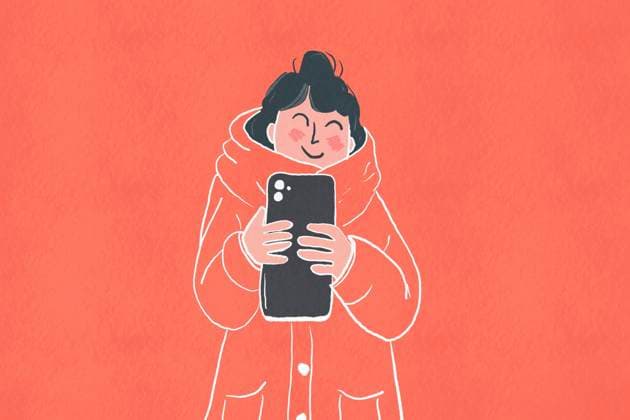 Creative Highlights Symbolfotos Illustration of a cheerful young woman wrapped in a cozy, thick winter coat using a smartphone against a warm-hued background Model Released HodeiUnzueta_ID23847_692176_006 Copyright: xHodeixUnzuetax RECORD DATE NOT STATED