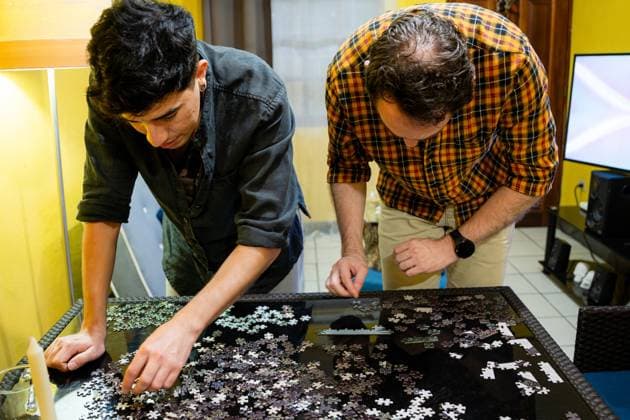 A gay couple engaged in piecing together a jigsaw puzzle, focusing intently on the pieces in a cozy home setting Model Released LeoTenorio_ID23751_689277_015 Copyright: xLeoxTenoriox RECORD DATE NOT STATED