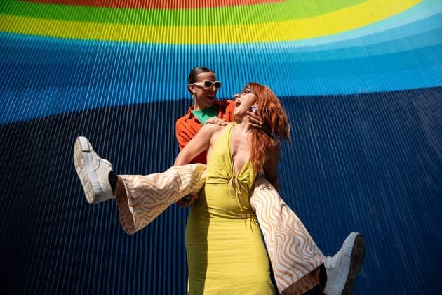 Creative Highlights Symbolfotos A joyful lesbian couple dances in front of a vibrant, rainbow-colored backdrop. One woman lifts the other as they share a moment of happiness, under the bright sunlight. Model Released ManuelRuiz_ID24145_699938_091 Copyright: xManuelxRuizx