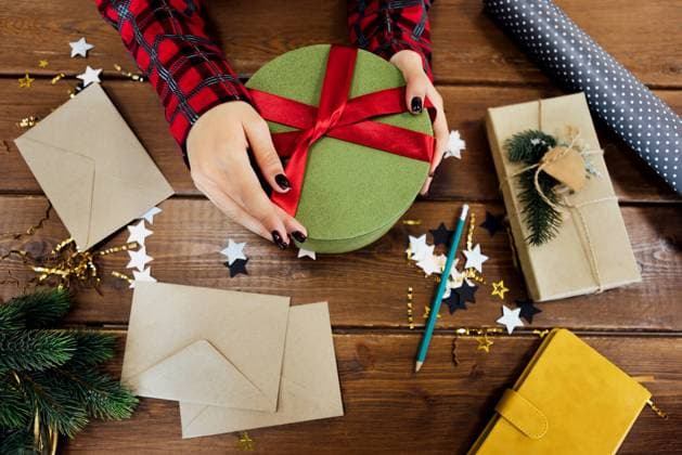 Close-up of young female dark-skinned hands with neat manicure holding new year gift on wooden table. Top view. Woman ties red bow on festive box. Close-up of young female dark-skinned hands with neat manicure holding new year gift on wooden table. Top view. Woman ties red bow on festive box. Wrapping Christmas presents. Preparing for holiday ,model released, Symbolfoto Copyright: xZoonar.com DashaxPetrenkox 22259575 ,model released, Symbolfoto ,property released