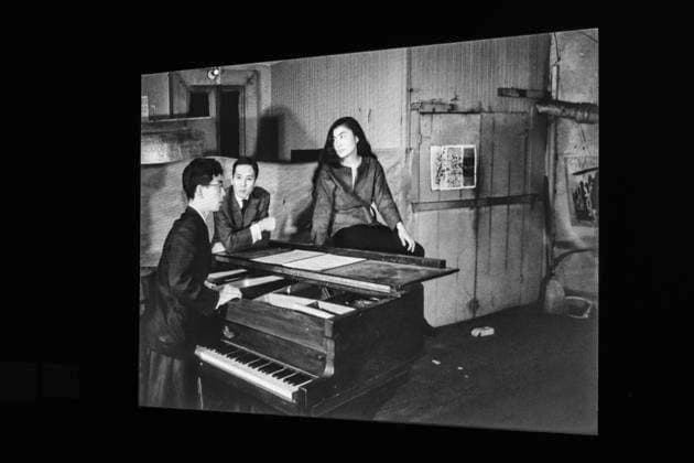 Solo exhibition Music of the Mind by Yoko Ono in Düsseldorf Black and white photo of Yoko Ono sitting on a grand piano projected onto the wall The photo was taken in 1960 or 1961 with other p