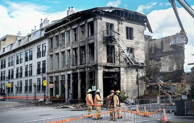 October 5, 2024, Montreal, Pq, Canada: Firefighters stand next to a building in Old Montreal on Saturday, Oct., 5, 2024. A fire that tore through a century-old building in Old Montreal killed at least two people and forced dozens of others out of the area, city police confirmed Saturday as they continued to probe what caused the building to catch alight. Montreal Canada  - ZUMAc35_ 20241005_zaf_c35_056 Copyright: xGrahamxHughesx