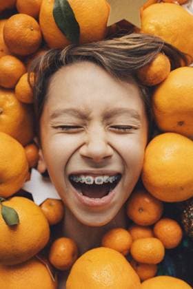 Creative Highlights Symbolfotos Portrait of a laughing boy s face in tangerines Shanghai, Shanghai, China CR_ITUP241004-1541865-01 ,model released, Symbolfoto