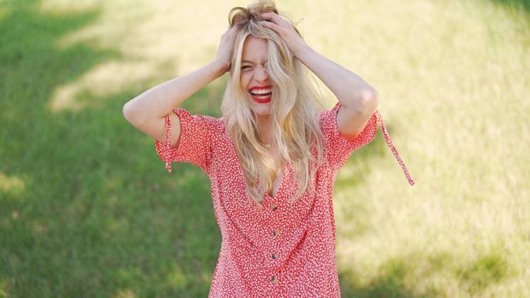 Creative Highlights Symbolfotos Joyful Woman Enjoying Sunny Day in Flowery Dress A cheerful young woman in a red floral dress stands in a sunlit field, exuding a feeling of joy and freedom. ,model released, Symbolfoto Copyright: xZoonar.com DanielxDashx 21490329 ,model released, Symbolfoto ,property released