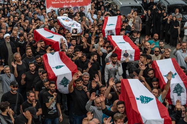 News Bilder des Tages October 14, 2024, Maaysrah, Maaysrah, Lebanon: A large crowd of people carry flag draped coffins during a mass funeral service for those killed in an Israeli airstrike. 15 people died in the attack, according to the Lebanese Ministry of Health. Maaysrah Lebanon - ZUMAw401 20241014_znp_w401_008 Copyright: xTimothyxWolferx