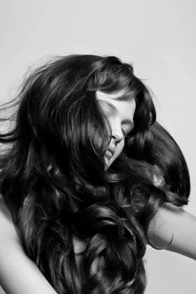 Creative Highlights Symbolfotos Black and white portrait of a person with voluminous, wavy hair covering their face, posing with a hand on their cheek. krst00443 Copyright: xConnectxImagesx ,model released