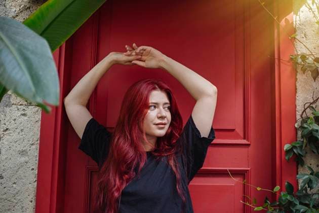 Creative Highlights Symbolfotos Young woman with long red hair stretching against of red door Alaçat?, ?zmir, Türkiye R_THNZ241015-1563625-01 ,model released, Symbolfoto