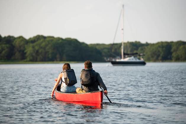 Couple with backpacks paddling canoe on summer day Charlestown, Rhode Island, United States CR_CABR241016-1548134-01 ,model released, Symbolfoto