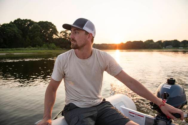 Man motoring through harbor at sunset in inflatable dinghy Charlestown, Rhode Island, United States CR_CABR241016-1548159-01 ,model released, Symbolfoto