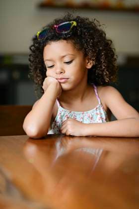 Creative Highlights Symbolfotos Pensive girl resting chin on hand, seated at a wooden table indo United States, Florida, Inverness CR_YWQX241014B-1556212-01 ,model released, Symbolfoto