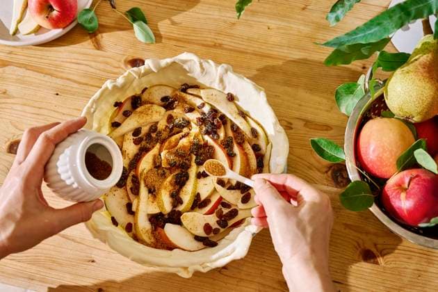 Hands of woman putting brown sugar over apple slices at table model released, Symbolfoto property released, CATF00339