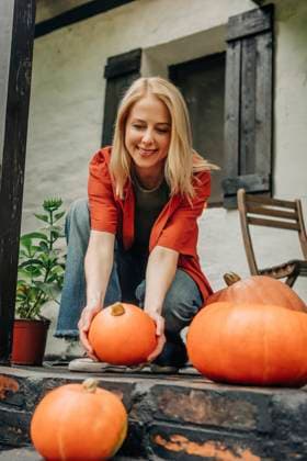 Smiling woman arranging pumpkins on porch model released, Symbolfoto property released, VSNF02509