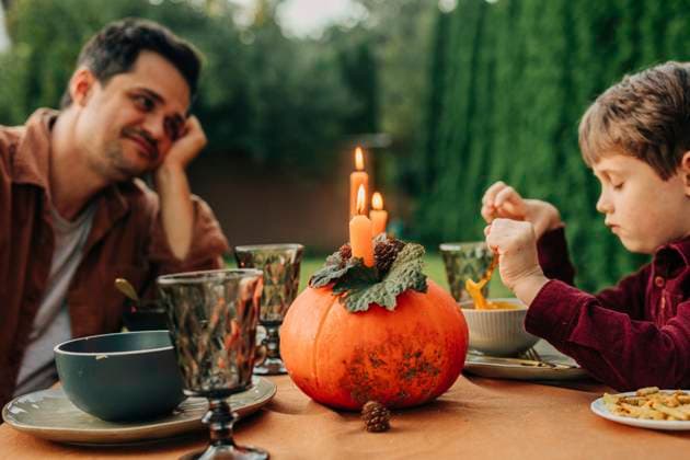 Smiling father with son having pumpkin soup at dining table model released, Symbolfoto, VSNF02582
