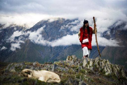 Creative Highlights Symbolfotos A woman in a red coat and beret walks with a stick on a rocky mountain with clouds and a dog in the foreground. 26393091 ,model released, Symbolfoto RECORD DATE NOT STATED