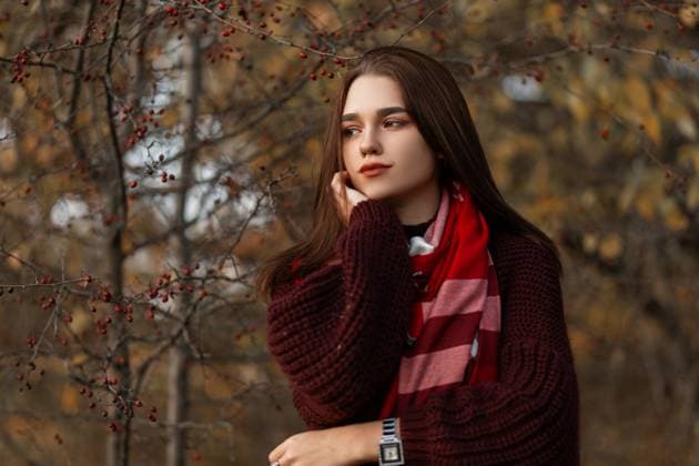 Attraktive junge Frau in einem burgunderroten trendigen Strickpullover mit einem roten stilvollen karierten Schal posiert im Park auf einem Hintergrund von trockenen Herbstbäumen. Nettes Mädchen Modell ruht im Freien im Wald. *** attractive Boy Woman in a burgundy trendy Knitted sweater with a Red stylish checkered Scarf poses at Park at a Background from Dry Autumn trees Nice Girls Model rests at Free at Forest 1102811853 ,model released, Symbolfoto