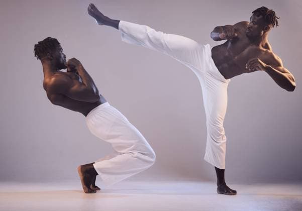 Creative Highlights Symbolfotos Sports, martial arts and black people with kick in studio for karate fitness, action exercise or learning. Grey background, teacher coaching or athletes fight in training challenge, workout or combat. model released property released Copyright: xwww.peopleimages.comx