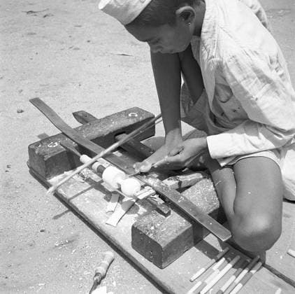 Young boy using portable rotating lathe applying lacquer wringtinforia wood ; painting lacquer toys ; Channapatna ; Karnataka Copyright: xTxSatyan DinodiaxPhotox