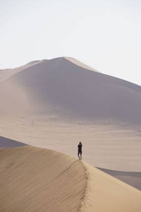 Creative Highlights Symbolfotos A lone person standing on a sand dune in a vast desert landscape with clear skies. 25732399 ,model released, Symbolfoto RECORD DATE NOT STATED
