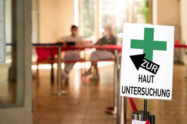 Germany - June 20, 2024: For a SKIN EXAMINATION! It says on a sign at a doctor s office or dermatologist s office. You can see medical assistants at the specialist. Symbolizes skin screenings that detect abnormalities and skin cancer as early as possible. PHOTOMONTAGE