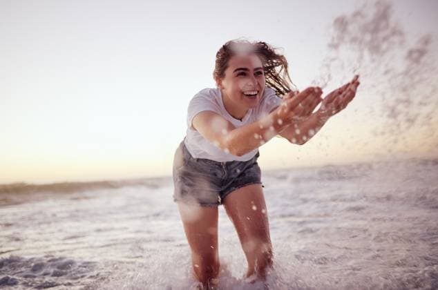 Creative Highlights Symbolfotos Splash, ocean and woman at the beach in the water, enjoying the waves at sunset. Summer adventure, holiday and happy girl having fun on vacation. Freedom, joy and playful female splashing in the sea. model released property released Copyright: xwww.peopleimages.comx