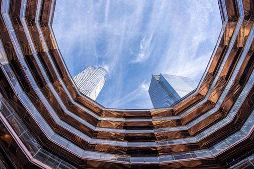 Creative Highlights World A low angle of an urban Vessel building at Hudson Yards under high skyscrapers and cloudy sky 24596077