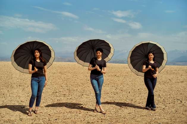 Creative Highlights Symbolbilder Three women holding black umbrellas standing in a desert with a clear blue sky background, Morocco bola04246 Copyright: xConnectxImagesx ,model released