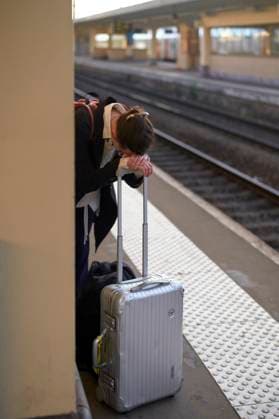 IMAGO Creative, Gesellschaft, Leisure Sickness Exhausted traveler resting on a suitcase at a train station platform. bola04432 Copyright: xConnectxImagesx ,model released