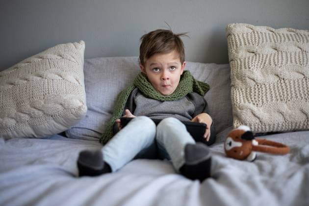 Young child sitting on bed making funny face while holding a tablet Norman, Oklahoma, United States CR_AOVS241028G-1567867-01 ,model released, Symbolfoto