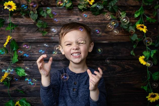 Creative Highlights Symbolbilder Smiling child playing with bubbles against a floral wood backdrop Norman, Oklahoma, United States CR_AOVS241103A0-1577611-01 ,model released, Symbolfoto