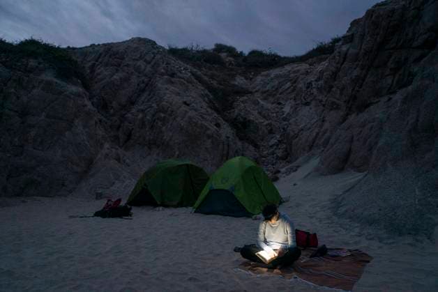 Creative Highlights Symbolbilder A woman reads by headlamp at beach campsite Cabo San Lucas, Baja California Sur, Mexico CR_AXTH241102-1559703-01 ,model released, Symbolfoto