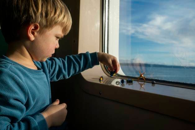 Creative Highlights Symbolbilder A 4 year-old boy plays with Legos on the ledge of a ferry boat window. Seattle, Washington, United States CR_AXTH241102-1559745-01 ,model released, Symbolfoto