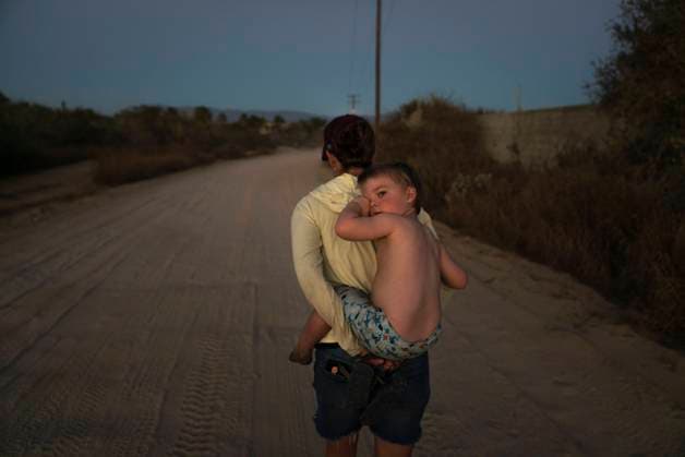 Creative Highlights Symbolbilder A 3-year-old boy rubs his eyes carried on his mom s back on dirt road Cabo San Lucas, Baja California Sur, Mexico CR_AXTH241102-1559817-01 ,model released, Symbolfoto