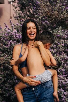 IMAGO Creative, Sommer, Sommertage im Garten Creative Highlights Symbolbilder Laughing mother embraces young son in front of purple flowers Joshua Tree, California, United States CR_FKNH241101B-1575533-01 ,model released, Symbolfoto