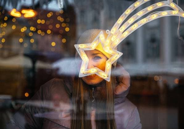 Creative Highlights Symbolbilder Woman smiling through illuminated star decoration Klagenfurt am Wörthersee, Carinthia, Austria R_GVYI241030-1573424-01 ,model released, Symbolfoto