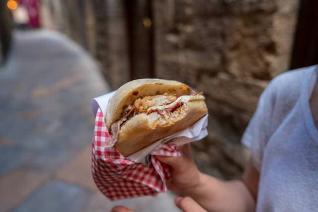 A close-up of a savory panini in the charming streets of Volterra, Tuscany The delightful presentation includes a checkered paper wrap, emphasizing traditional Italian street food culture Model Released JuanAlbertoRuiz_ID24636_713869_006 Copyright: xJuanxAlbertoxRuizx RECORD DATE NOT STATED