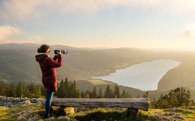 MR_ID24663_18733_NataliaDuqueJaramillo.jpg Back view of unrecognizable woman using a camera to capture the serene sunset in Dent de Vaulion, overlooking a scenic Swiss lake. Model Released NicoescobarPhoto_ID24663_714582_015 Copyright: xNicoescobarxPhotox