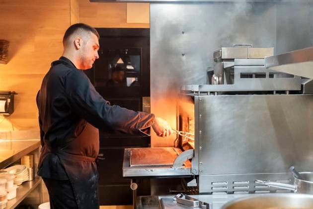 An expert chef serving meals in the bustling kitchen of a restaurant, surrounded by steam due to the use of the grill in the kitchen Model Released PaulaBerezo_ID24490_709733_007 Copyright: xPaulaxBerezox RECORD DATE NOT STATED