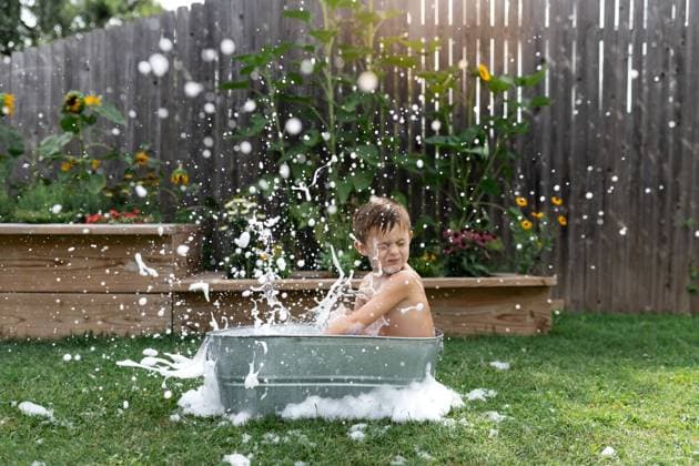 IMAGO Creative, Sommer, Sommertage im Garten Child splashes in a metal tub outdoors, surrounded by garden flowers. Norman, Oklahoma, United States CR_AOVS241111B-1577587-01 ,model released, Symbolfoto