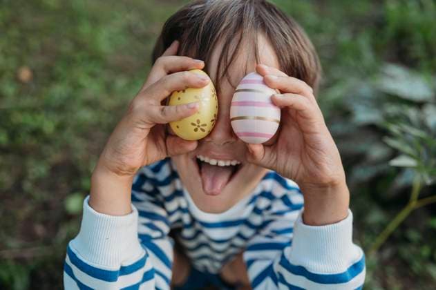 Boy sticking out tongue and cover eyes with easter eggs in park model released, Symbolfoto, ANAF04055