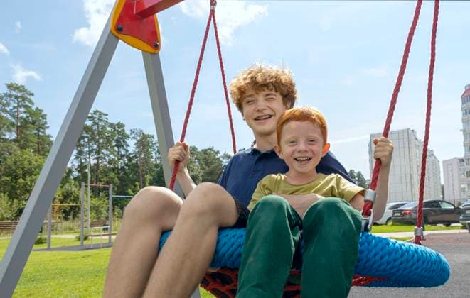 Cheerful brothers enjoying on swing at playground model released, Symbolfoto, MBLF00675